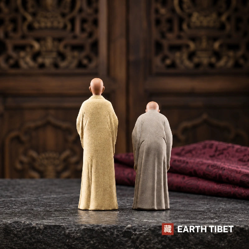 Back view of both monk statues showing the fall of the unglazed robes and the height difference