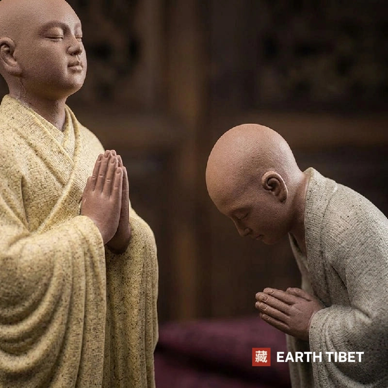 Close view of the joined palms and the bowed head on the two novice monk statues